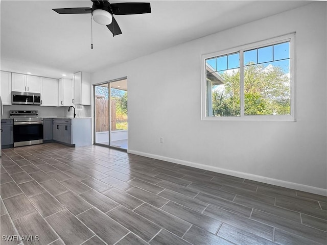 kitchen featuring ceiling fan, stainless steel appliances, sink, and white cabinets