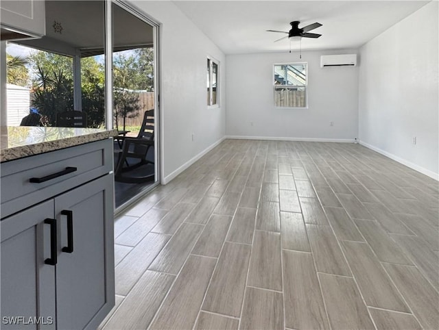 unfurnished dining area featuring a ceiling fan, a wealth of natural light, a wall unit AC, and wood finish floors