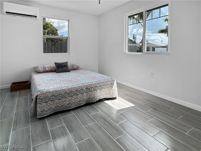 bedroom with wood finish floors, a wall mounted air conditioner, and baseboards