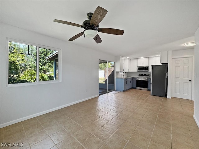 kitchen with light tile patterned floors, baseboards, white cabinets, ceiling fan, and appliances with stainless steel finishes