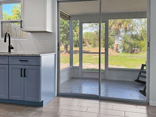 interior space with light stone counters, wood finish floors, a sink, and gray cabinetry