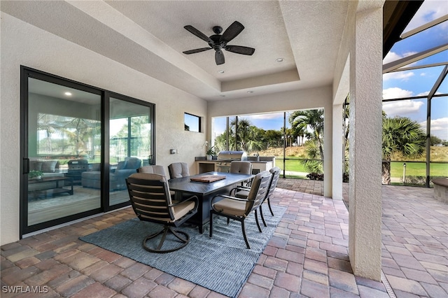 sunroom / solarium featuring a raised ceiling and ceiling fan