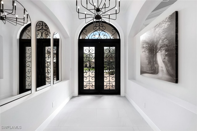 entrance foyer featuring a wealth of natural light, a notable chandelier, and french doors