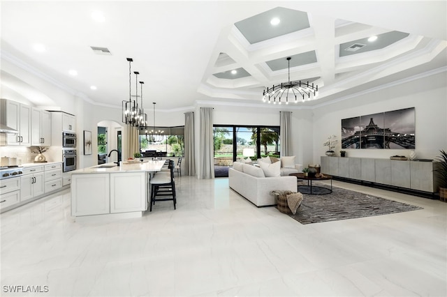 living area featuring a notable chandelier, visible vents, coffered ceiling, and ornamental molding