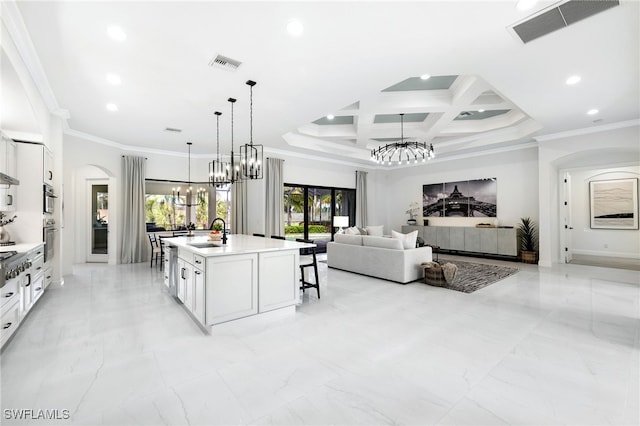 kitchen with a notable chandelier, sink, a kitchen island with sink, and white cabinets