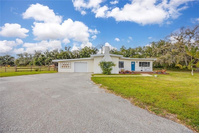 ranch-style home with aphalt driveway, an attached garage, fence, a front yard, and stucco siding