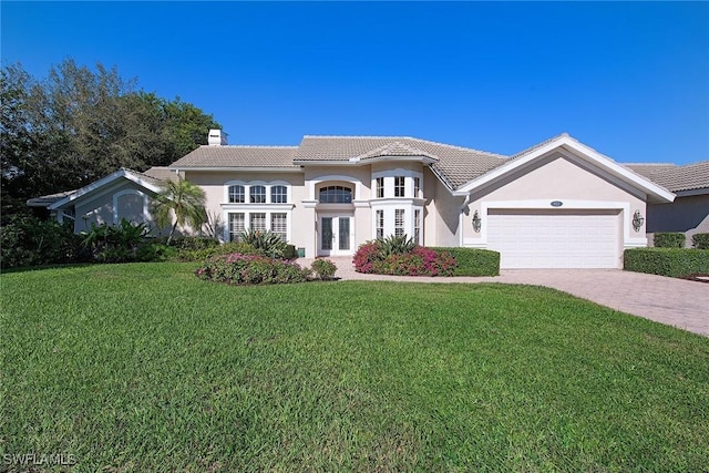 mediterranean / spanish home with french doors, a garage, and a front lawn