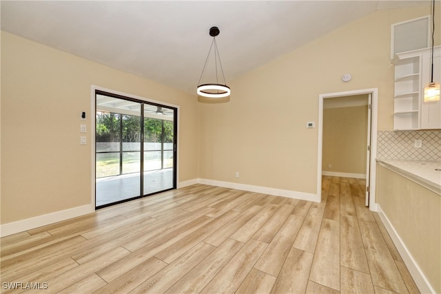 unfurnished dining area featuring vaulted ceiling and light hardwood / wood-style flooring