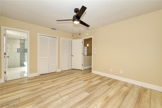 unfurnished bedroom featuring ceiling fan, connected bathroom, two closets, and light hardwood / wood-style floors