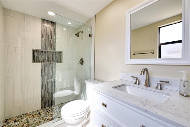 bathroom featuring vanity, tiled shower, and toilet