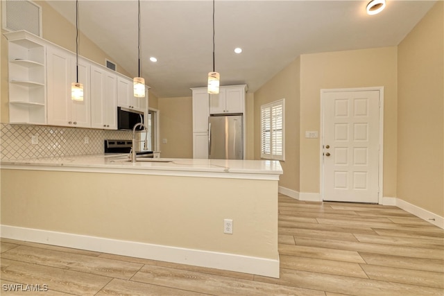 kitchen featuring white cabinetry, tasteful backsplash, kitchen peninsula, pendant lighting, and stainless steel appliances