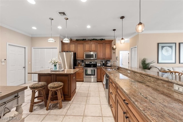 kitchen with a sink, a kitchen breakfast bar, hanging light fixtures, appliances with stainless steel finishes, and a center island