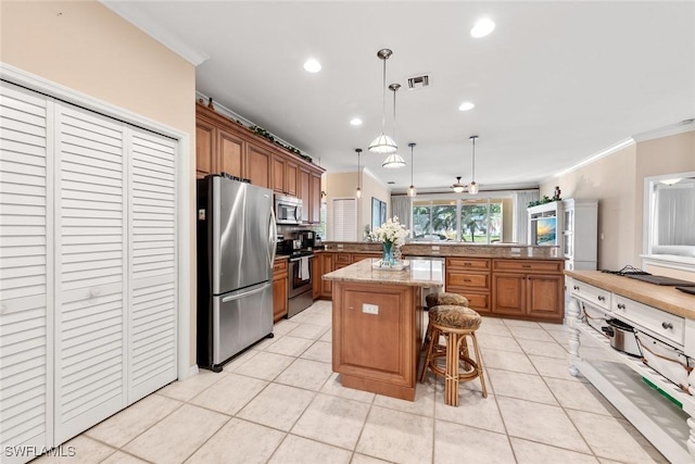 kitchen featuring visible vents, a kitchen island, appliances with stainless steel finishes, a breakfast bar, and pendant lighting