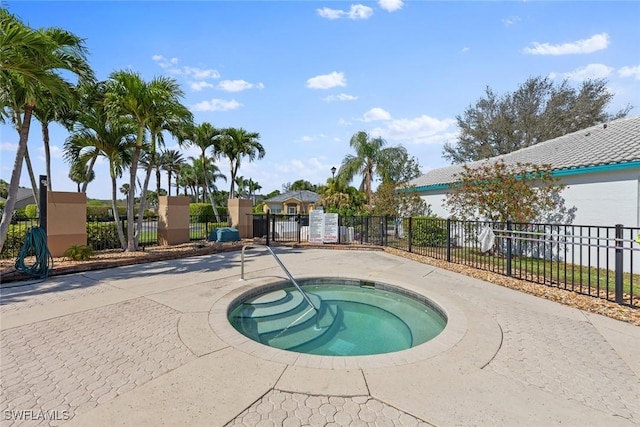 view of pool with fence and a hot tub