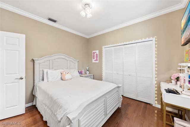 bedroom with ornamental molding, a closet, and dark wood finished floors