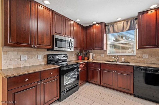 kitchen with sink, black appliances, light stone counters, and decorative backsplash