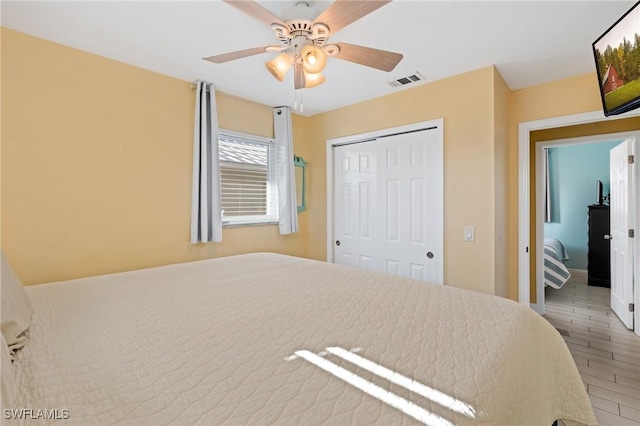 bedroom featuring ceiling fan, wood-type flooring, and a closet