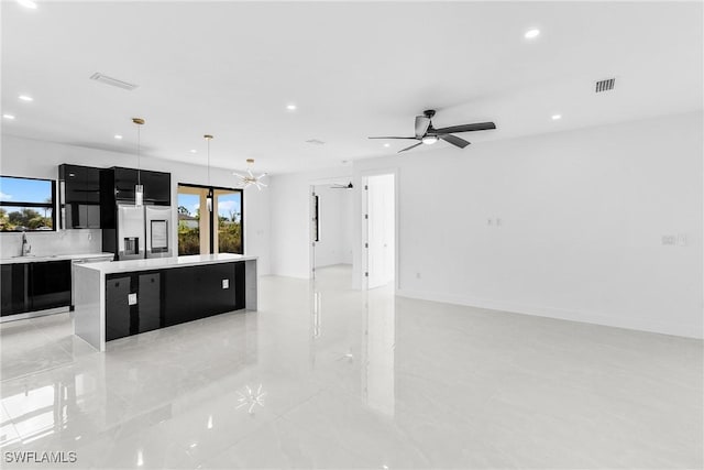 kitchen featuring visible vents, stainless steel fridge with ice dispenser, a kitchen island, hanging light fixtures, and light countertops