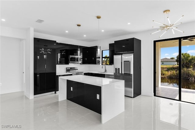 kitchen featuring dark cabinets, stainless steel appliances, a kitchen island, light countertops, and decorative light fixtures