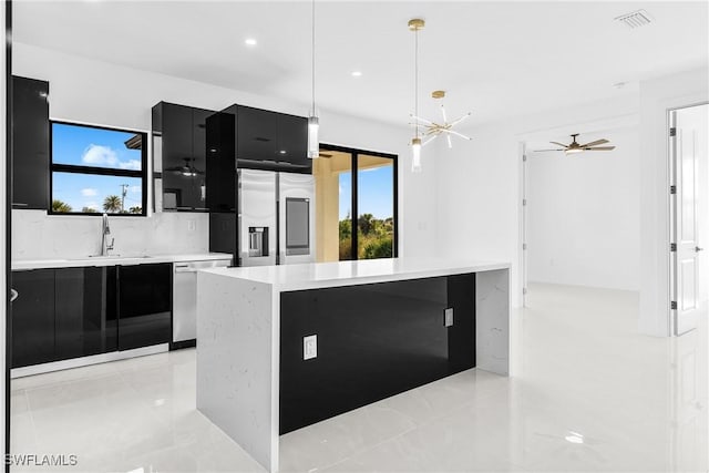 kitchen with pendant lighting, stainless steel appliances, light countertops, a sink, and dark cabinets