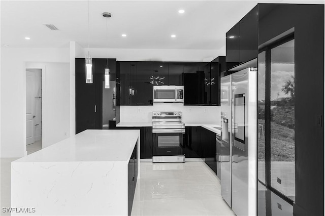 kitchen featuring stainless steel appliances, light countertops, dark cabinetry, modern cabinets, and pendant lighting