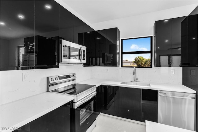 kitchen featuring stainless steel appliances, tasteful backsplash, a sink, modern cabinets, and dark cabinets