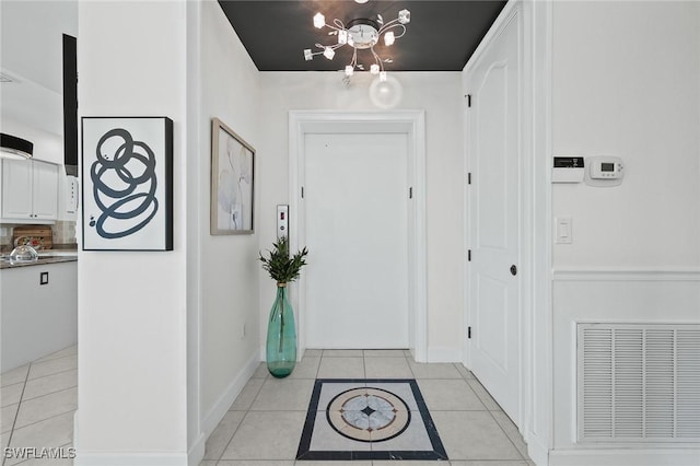 foyer with light tile patterned floors, baseboards, visible vents, and a notable chandelier