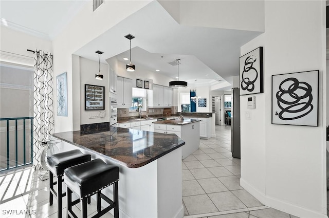 kitchen featuring white cabinets, visible vents, a sink, and a peninsula