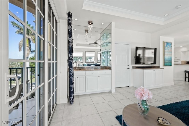 interior space with light tile patterned flooring, a sink, white cabinetry, and crown molding