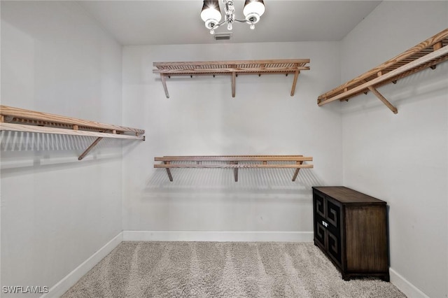 spacious closet with carpet flooring, a notable chandelier, and visible vents