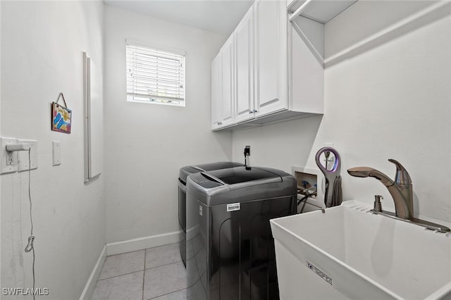 laundry room featuring light tile patterned floors, a sink, baseboards, cabinet space, and washer and clothes dryer