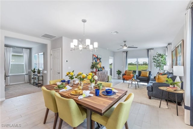 dining room with ceiling fan with notable chandelier, light wood-type flooring, and visible vents