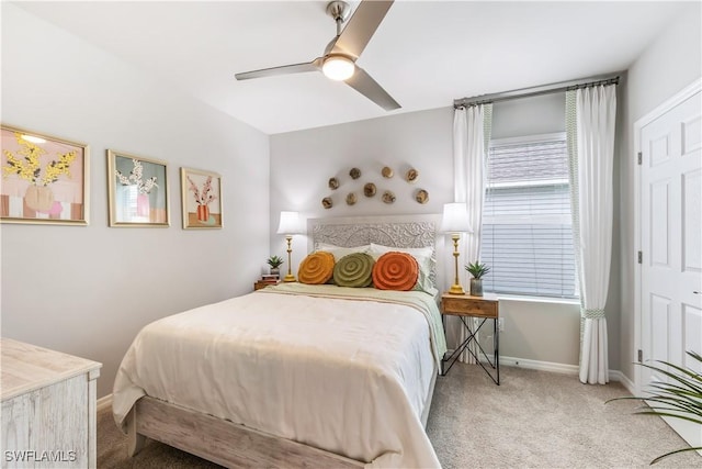 carpeted bedroom with ceiling fan and baseboards