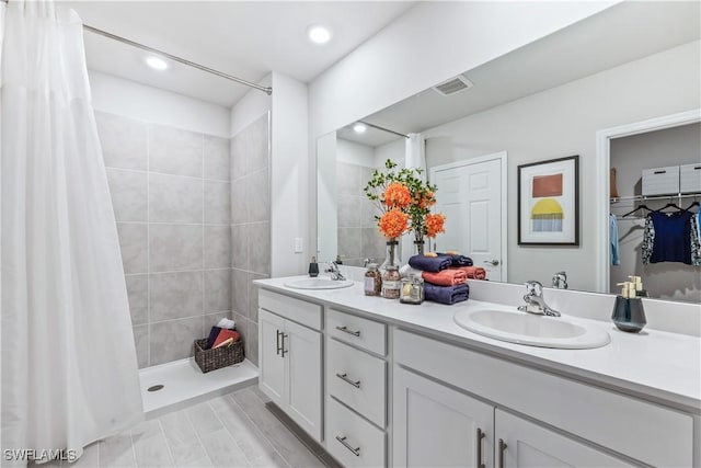 full bath with a stall shower, a walk in closet, a sink, and double vanity