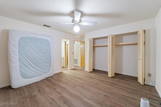 unfurnished bedroom featuring wood-type flooring, two closets, and ceiling fan