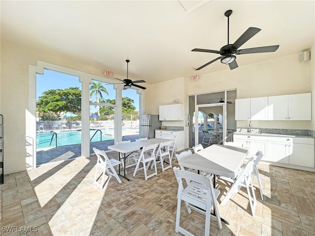 view of patio featuring a community pool, sink, ceiling fan, and an outdoor kitchen