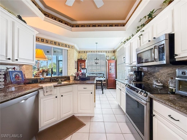 kitchen with sink, white cabinetry, hanging light fixtures, appliances with stainless steel finishes, and a raised ceiling