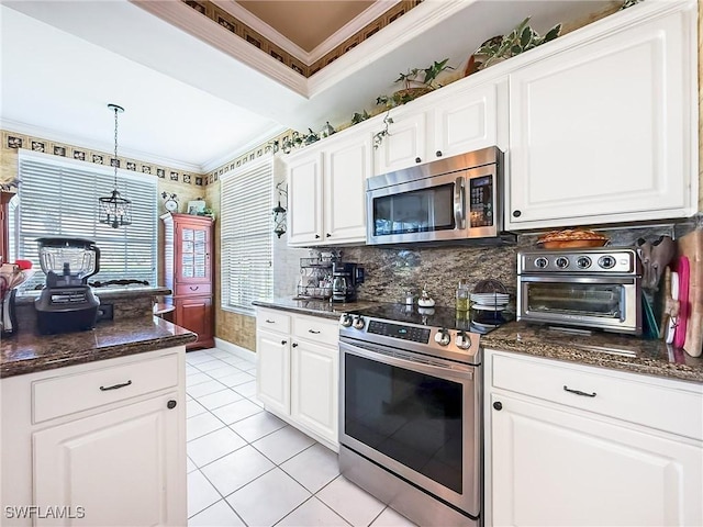 kitchen with hanging light fixtures, crown molding, stainless steel appliances, and white cabinets