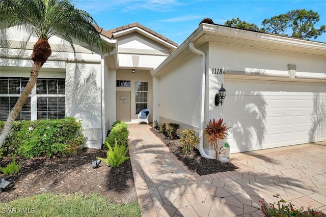 1118 Dorchester Ct, Naples, FL 34104 - doorway to property featuring a garage, stucco siding, and driveway