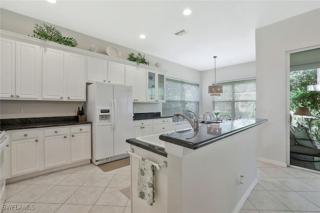 1118 Dorchester Ct, Naples, FL 34104 - kitchen featuring light tile patterned floors, dark countertops, white refrigerator with ice dispenser, and visible vents