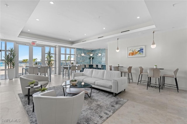 living area featuring a tray ceiling, visible vents, and recessed lighting