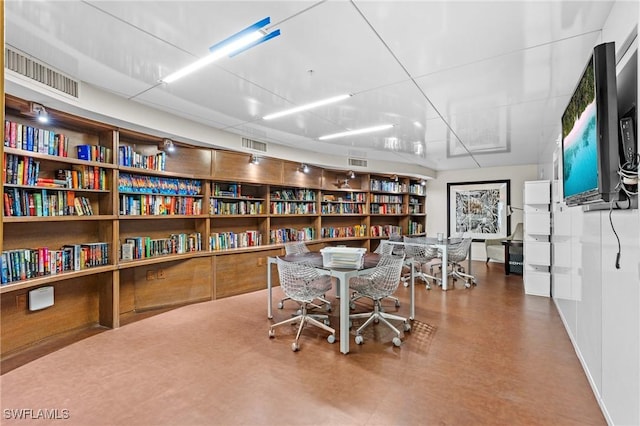 office area featuring wall of books and visible vents