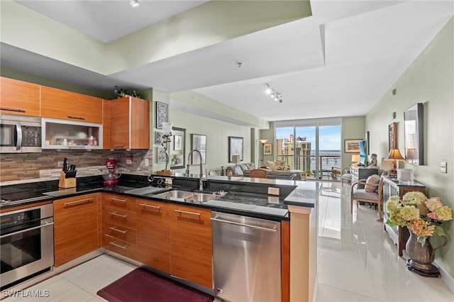 kitchen with stainless steel appliances, open floor plan, brown cabinetry, and a peninsula