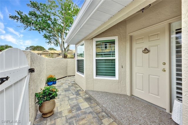 entrance to property featuring a patio area, fence, and stucco siding