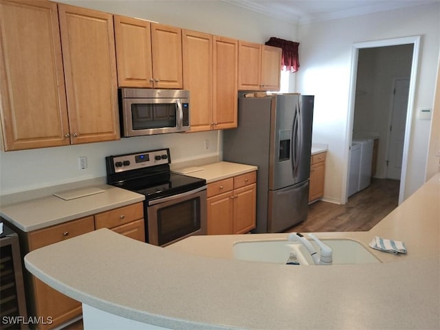 kitchen featuring sink, crown molding, stainless steel appliances, separate washer and dryer, and beverage cooler