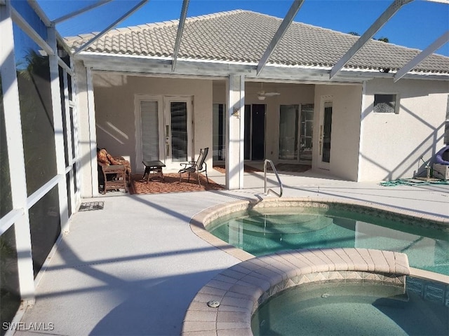 back of property with ceiling fan, a lanai, a pool with hot tub, and a patio