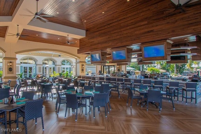 dining space with ceiling fan, parquet flooring, wooden ceiling, and a high ceiling