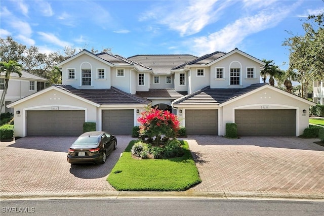 view of front of home featuring decorative driveway, a tiled roof, and stucco siding