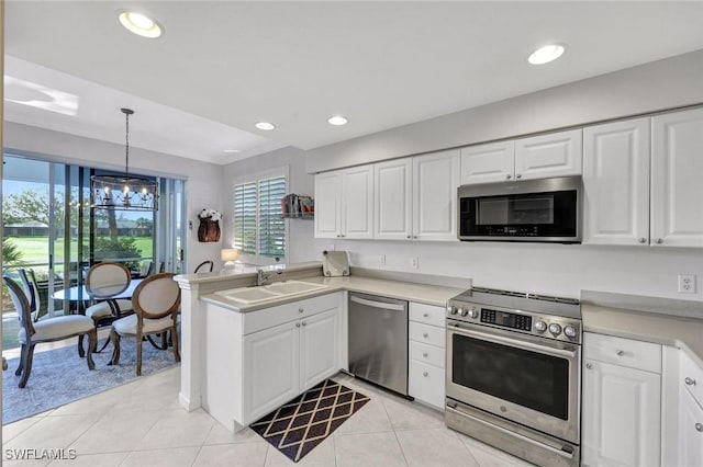 kitchen featuring a peninsula, white cabinets, stainless steel appliances, and a sink