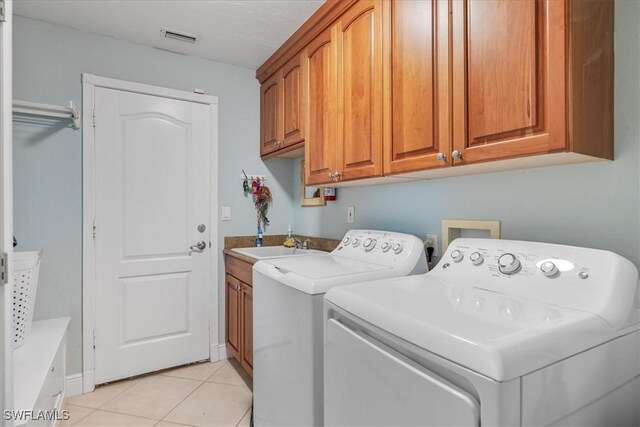 washroom with cabinets, sink, light tile patterned floors, and washing machine and clothes dryer